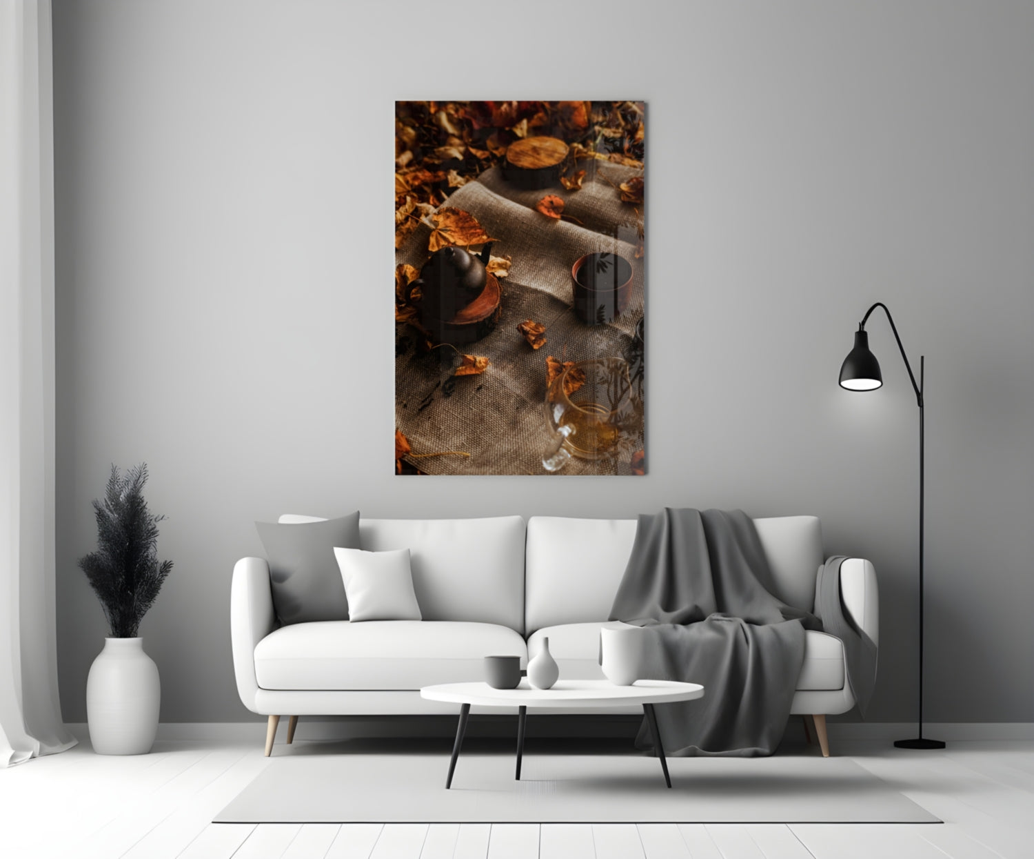 Autumn Picnic Glass Art displayed above a white sofa, showing dark bottles and scattered golden leaves on textured fabric.