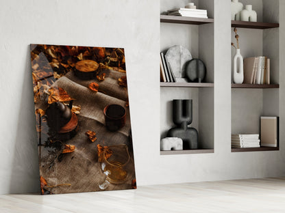Autumn Picnic glass art leaning against white wall, displaying warm-toned overhead view of teapot, mug, and fall leaves on linen.