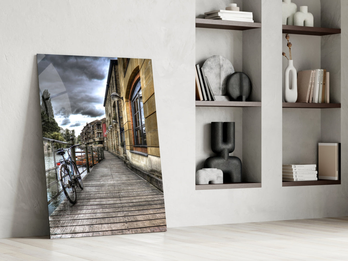 Glass wall art leaning against white wall displaying European canal street scene with bicycle and historic architecture.