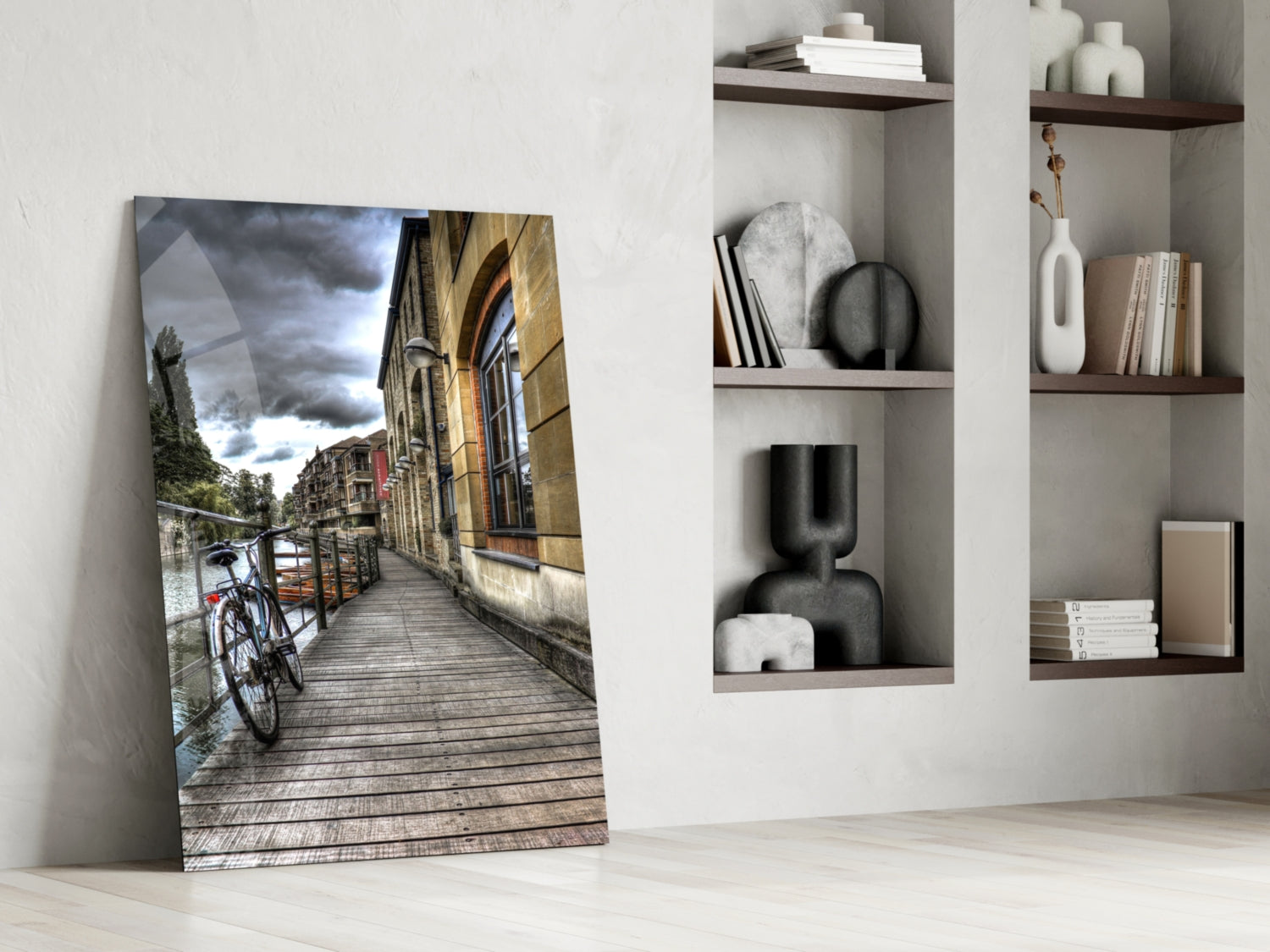 Glass wall art leaning against white wall displaying European canal street scene with bicycle and historic architecture.