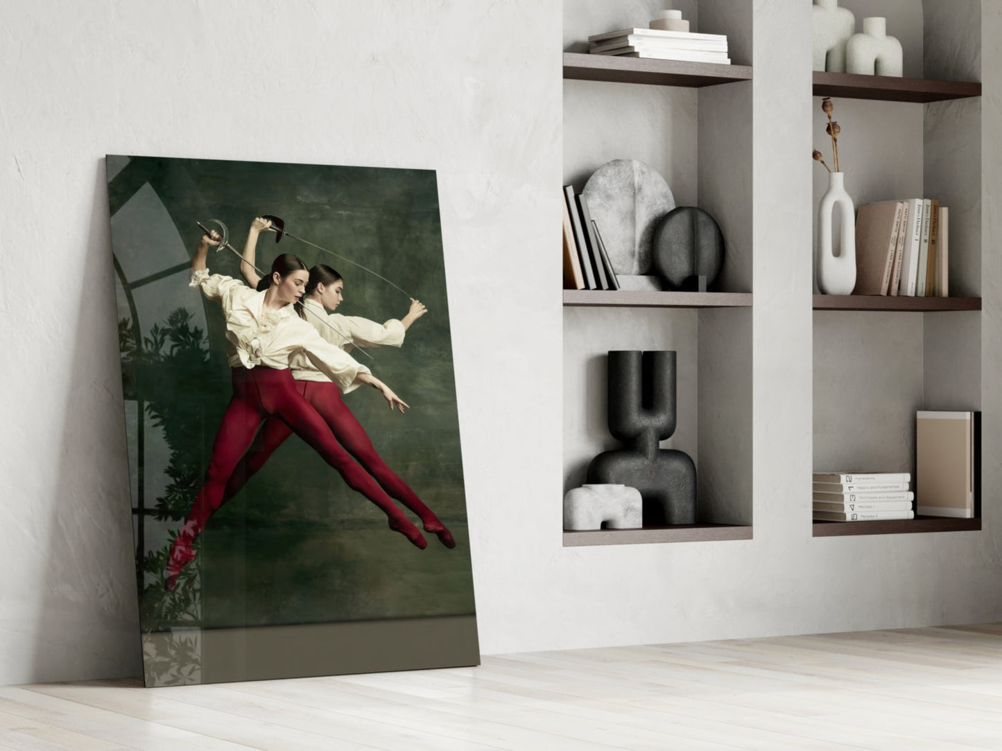 Leaning glass wall art depicting two fencers in cream shirts and red pants against dark green background, displayed in minimalist interior with white shelving.