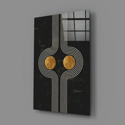 Black glass wall art with white geometric line patterns and two gold circular accents, displayed at an angle against gray background.