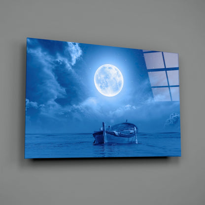 Angled view of glass wall art displaying a moonlit seascape with a boat, mounted on gray wall showing the product's depth and translucent edges.