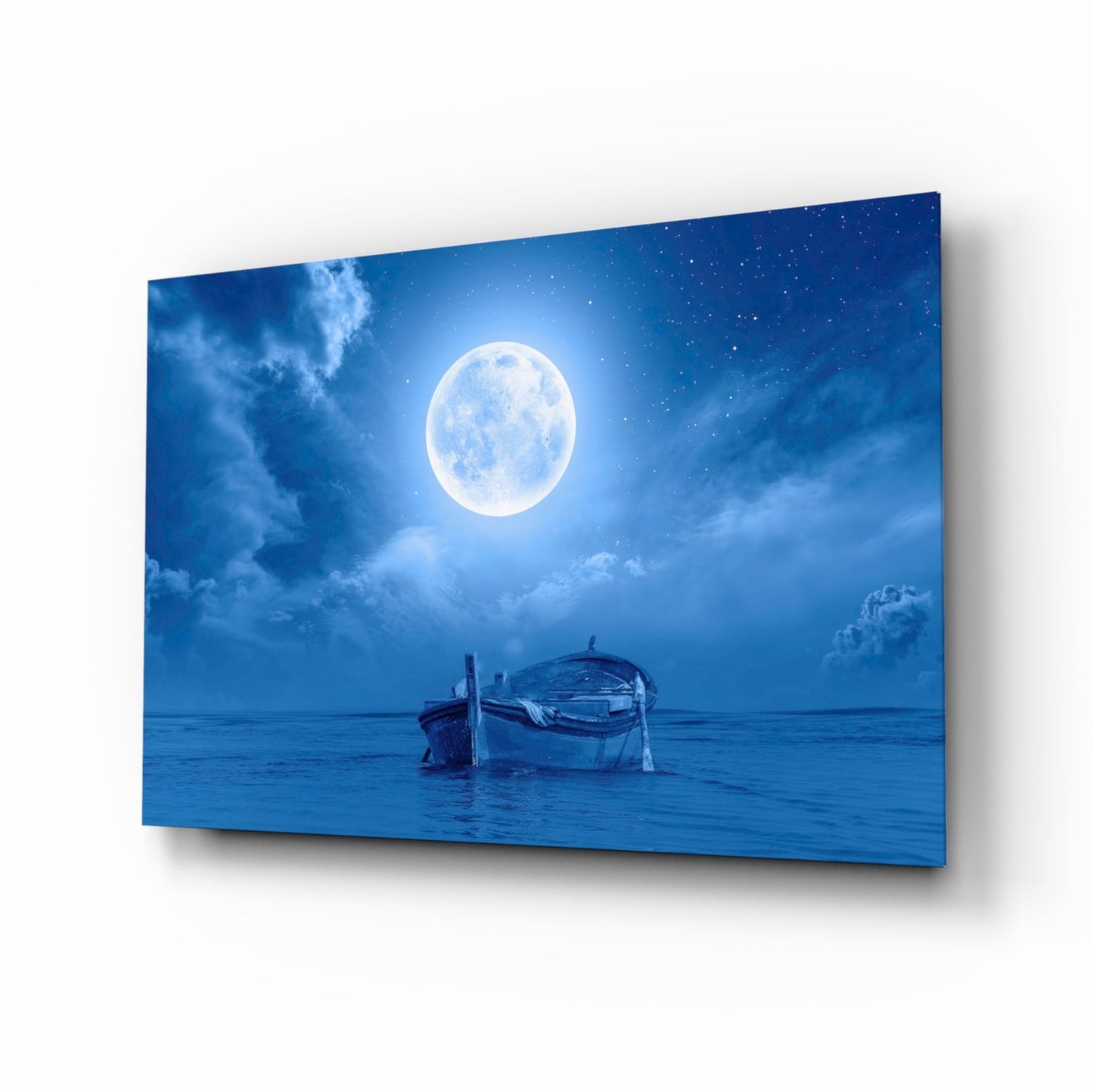 Glass wall art panel displaying a moonlit seascape with a wooden boat on calm blue water under a full moon and starry sky.