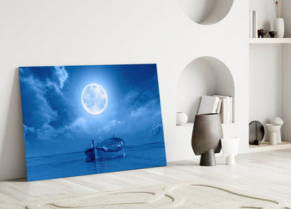 Blue glass wall art depicting a full moon over water with a boat, displayed in a minimalist white room with shelving.