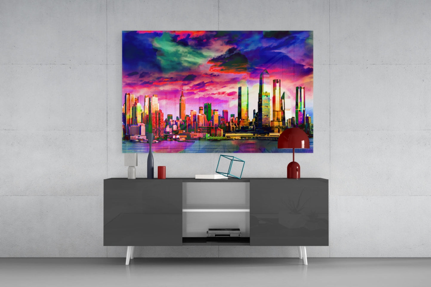 Vibrant neon cityscape glass art hanging above gray media console with red lamp and decorative accessories.