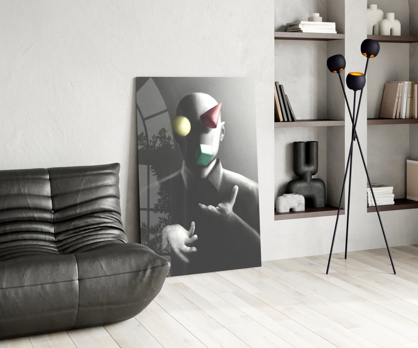Modern living room interior featuring grayscale glass wall art of a figure with colorful geometric shapes on face, displayed next to black leather sofa.
