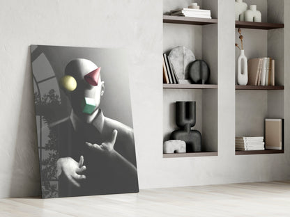 Juggler Glass Wall Art leaning against white wall beside shelving unit, displaying stylized figure with yellow and pink geometric shapes on gray background.