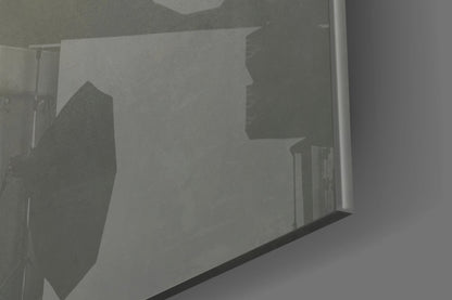 Close-up detail of frosted glass wall art showing silhouetted mask profiles etched into translucent surface with dark frame edge visible.