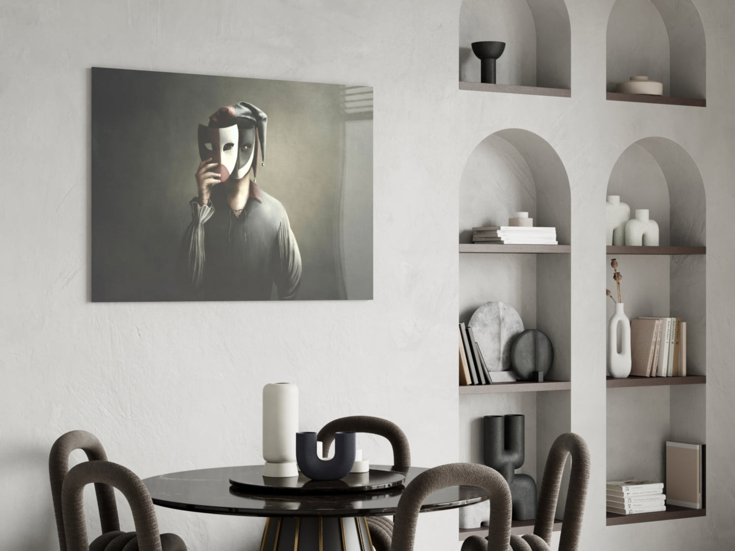 Glass wall art depicting a figure holding theatrical masks displayed above a black dining table in a minimalist interior setting.
