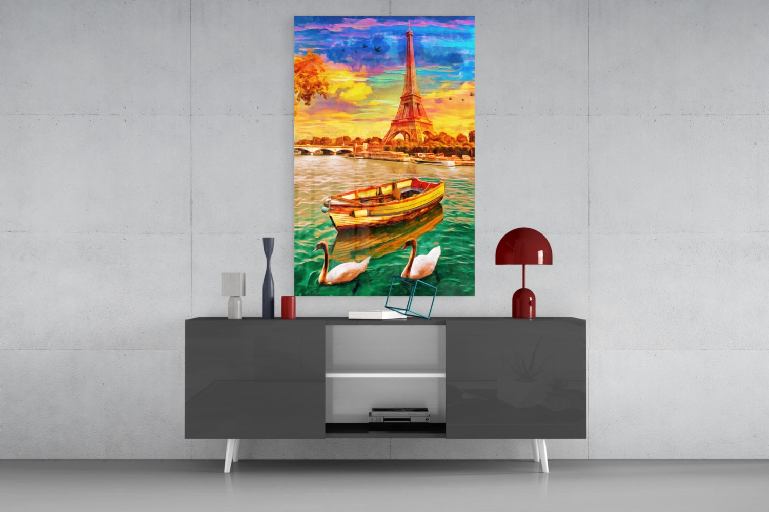 Colorful glass wall art depicting the Eiffel Tower, boat, and swans displayed above a dark console table in a modern interior setting.