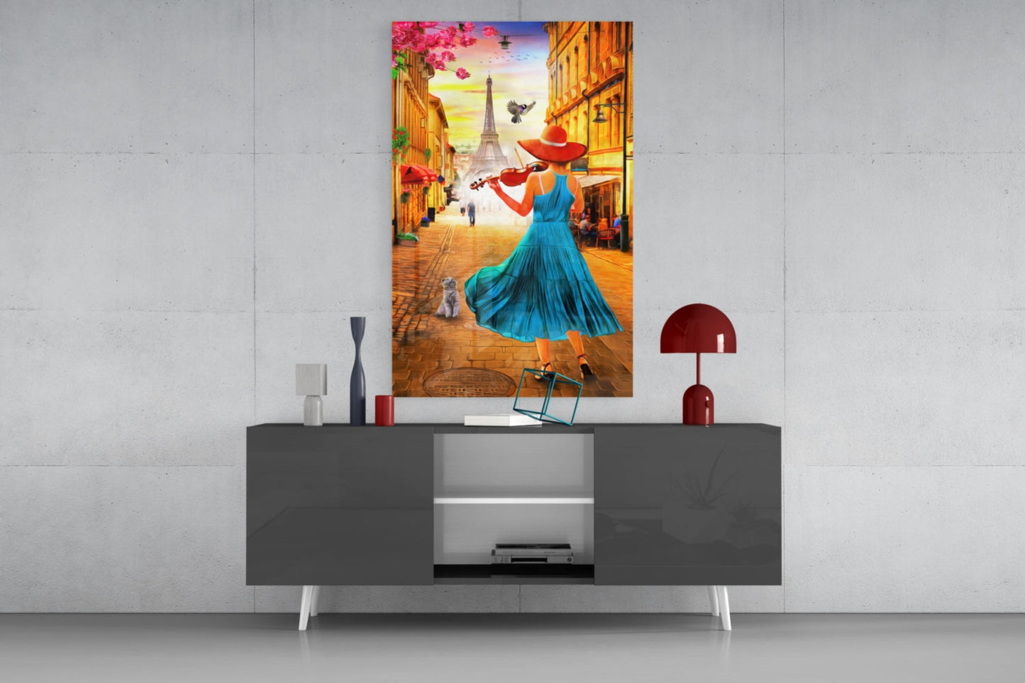 Colorful glass wall art depicting a woman in blue dress playing violin on a Parisian street, displayed above a modern grey console table.
