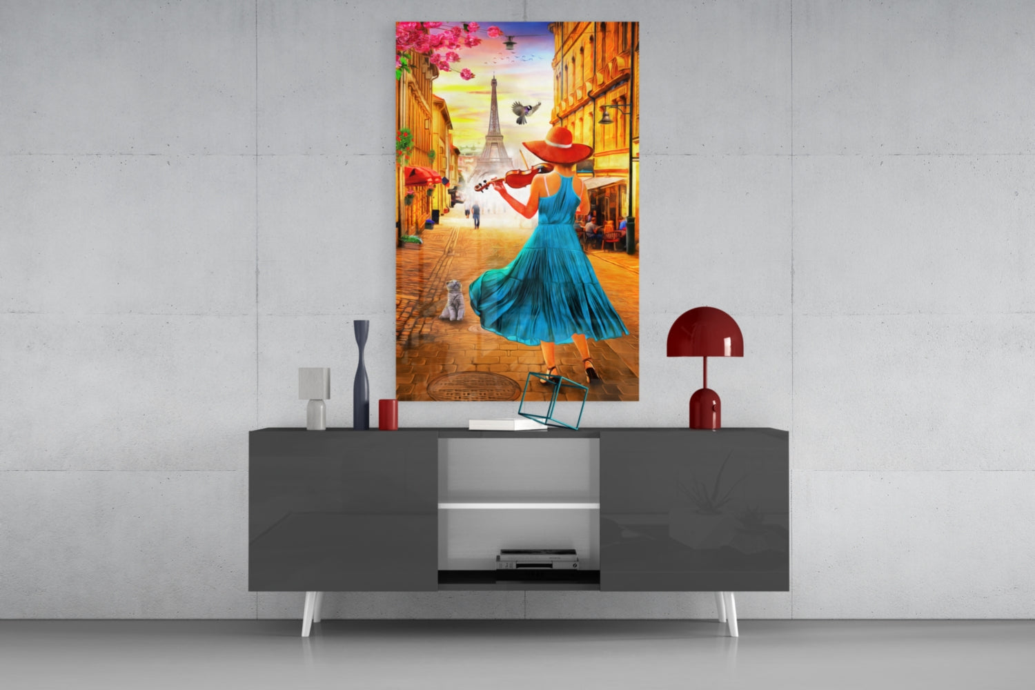 Colorful glass wall art depicting a woman in blue dress playing violin on a Parisian street, displayed above a modern grey console table.