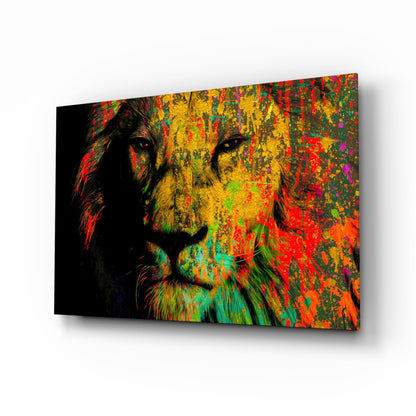 Angled perspective view of colorful glass wall art featuring a lion's face with vibrant splattered paint effects in red, yellow, green, and orange against black background.