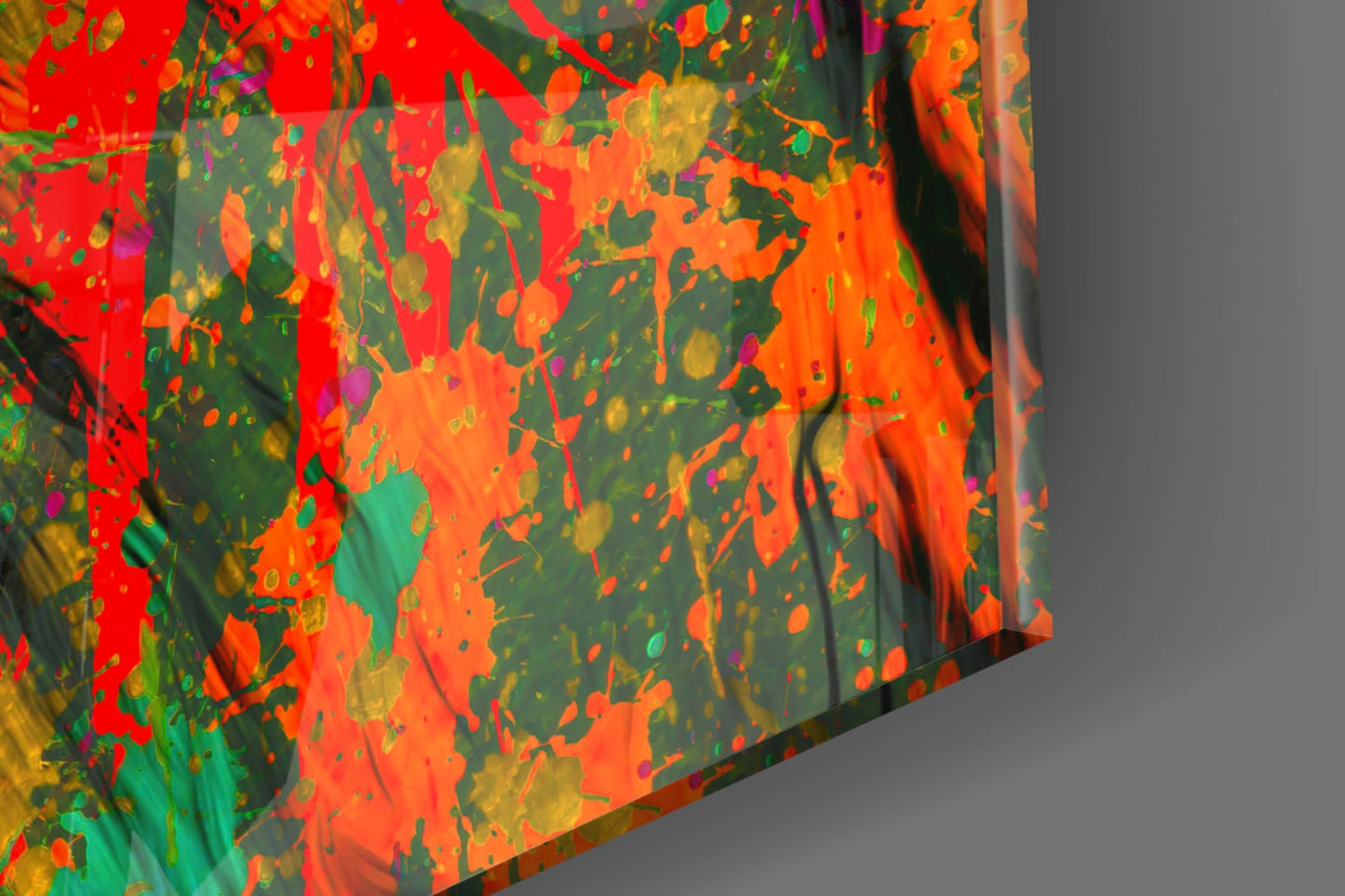 Close-up detail of colorful glass wall art showing vibrant splashes of red, orange, green, and yellow paint effects on dark base.