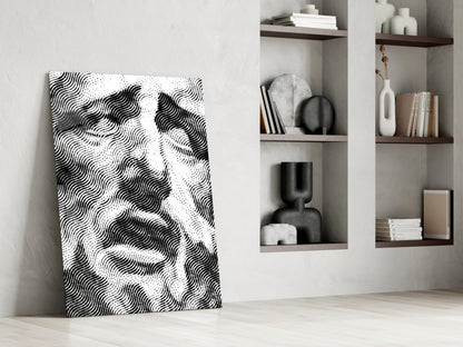 Black and white wavy striped glass art leaning against white wall beside shelving unit with decorative objects.