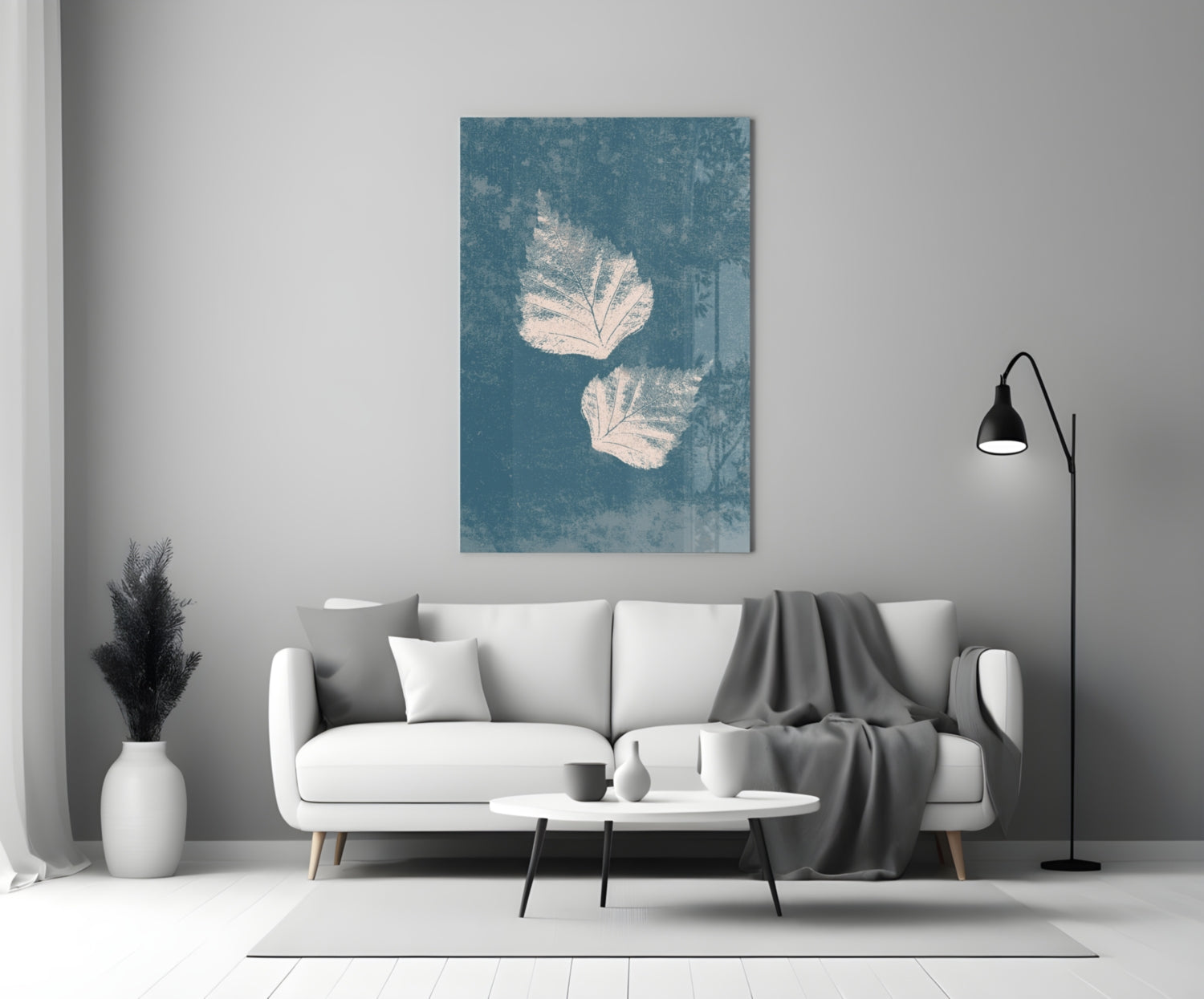 Teal glass wall art with white leaf prints displayed above a white sofa in a minimalist living room.