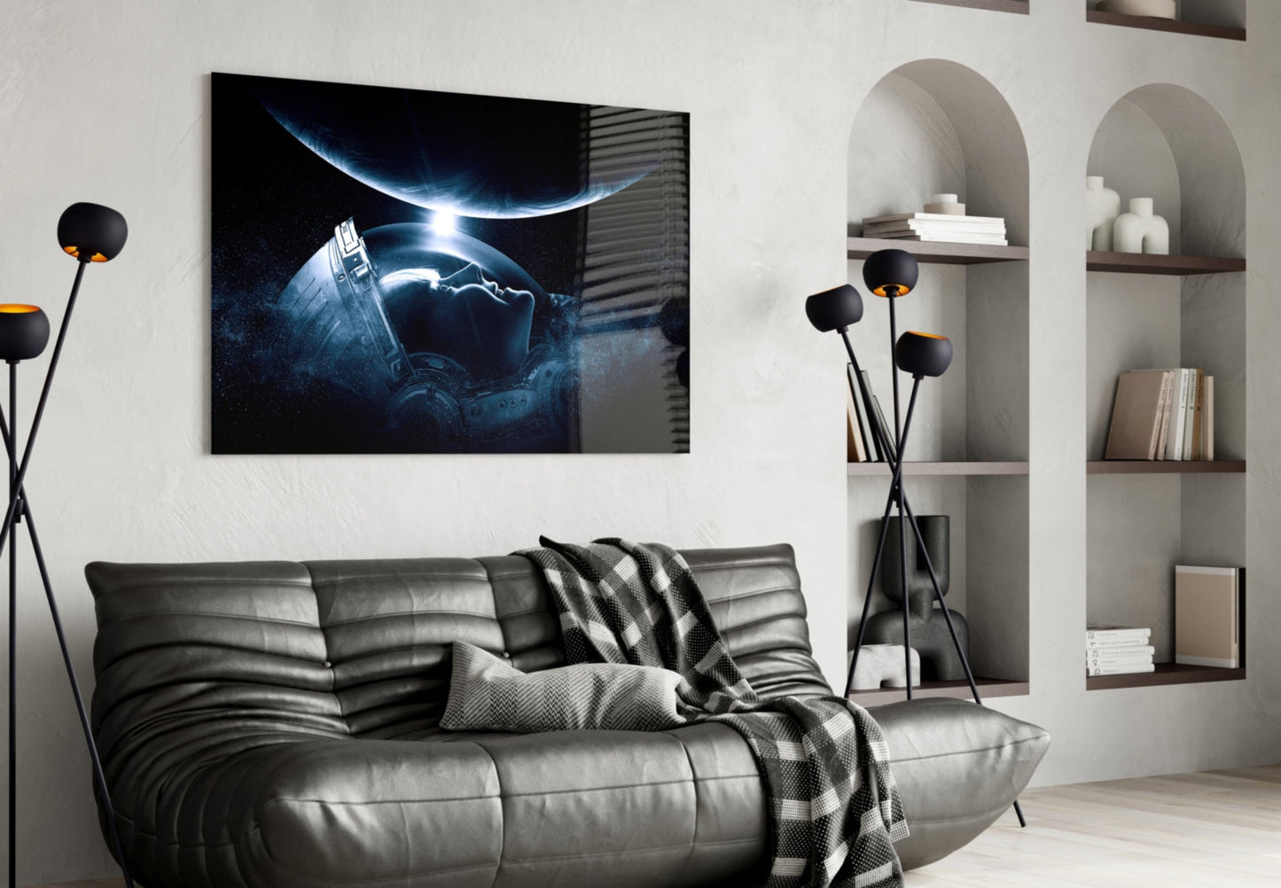Black framed astronaut space artwork hanging above gray leather sofa in modern living room with white shelving.