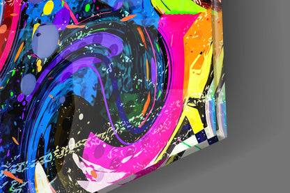 Colorful glass wall art featuring vibrant neon pink, blue, purple, yellow, and black swirled patterns photographed at an angled perspective against gray background.