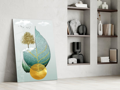 Glass wall art leaning against white wall displays gold tree and layered teal, green, and yellow leaves with birds.