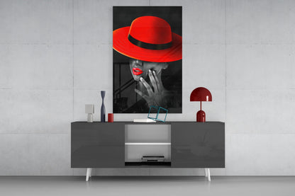 Black and white portrait with red hat and lips displayed above dark console table with white legs and red decorative accessories.