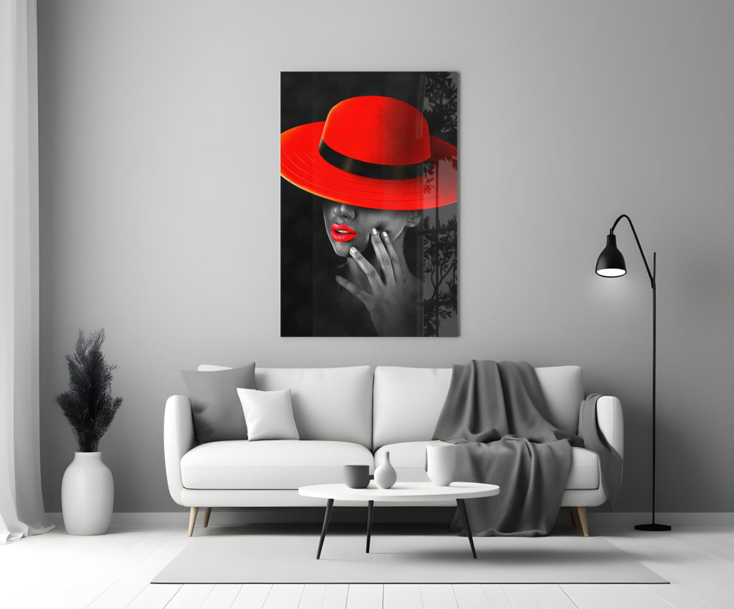 Scarlet Hat Glass Wall Art displayed above a white sofa in a modern living room setting, showing a black and white portrait with vibrant red hat and lips.
