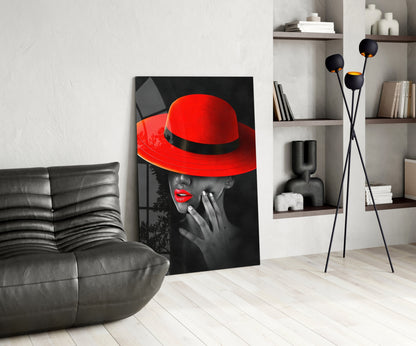Modern living room interior with black leather sofa, portrait glass art featuring woman in red hat against monochrome background, and floor lamp with black spherical shades.