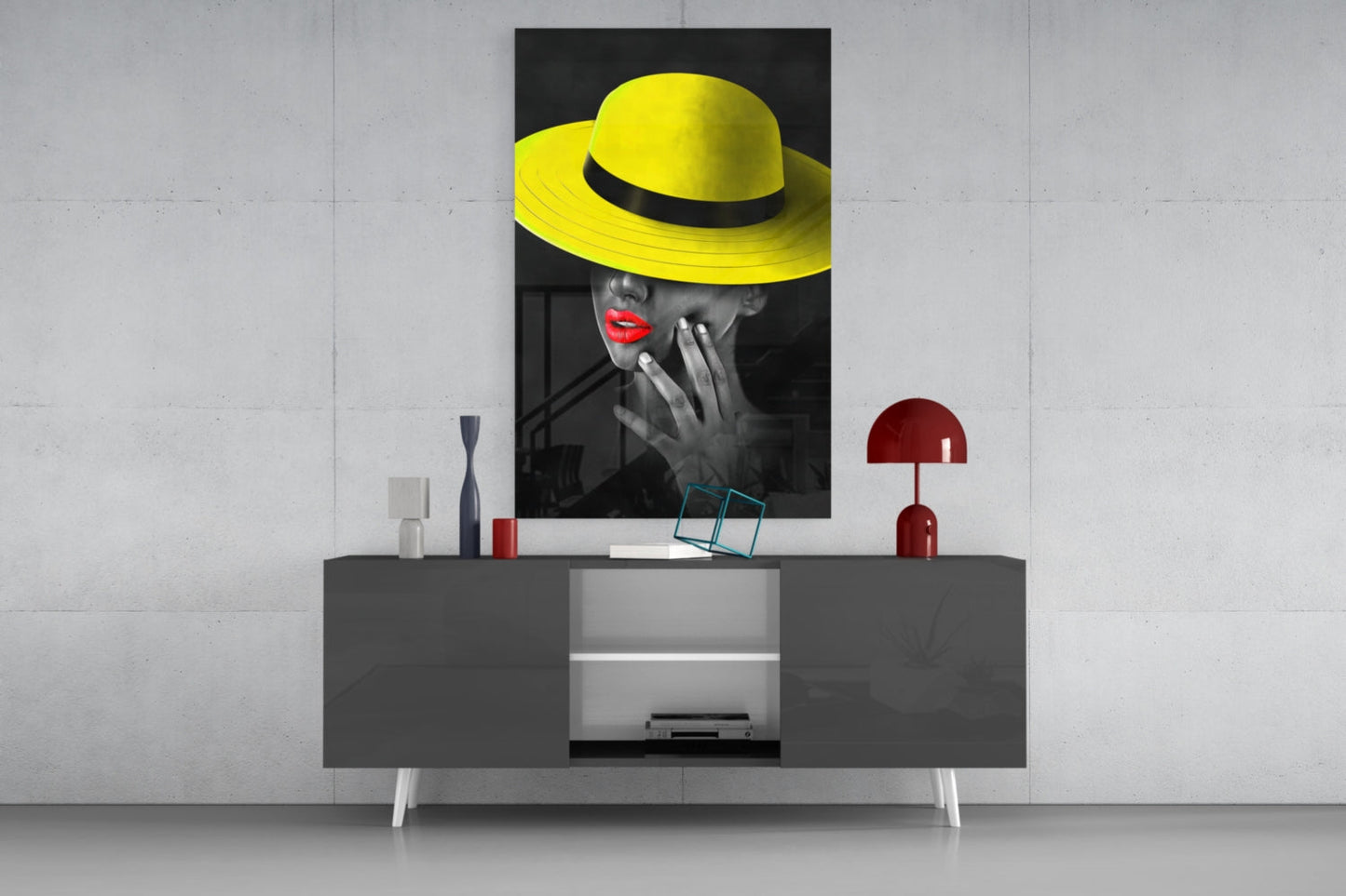 Yellow Hat Glass Wall Art displayed above a gray media console with red accents and decorative items in a modern interior setting.