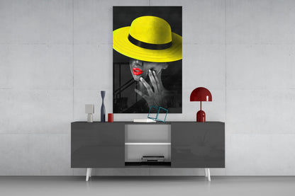 Yellow Hat Glass Wall Art displayed above a gray media console with red accents and decorative items in a modern interior setting.