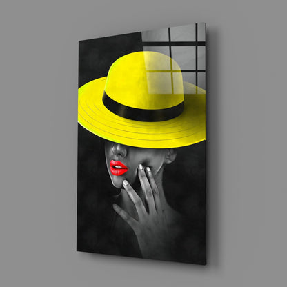 Angled product view of glass wall art featuring a black and white portrait with bright yellow hat and red lips.