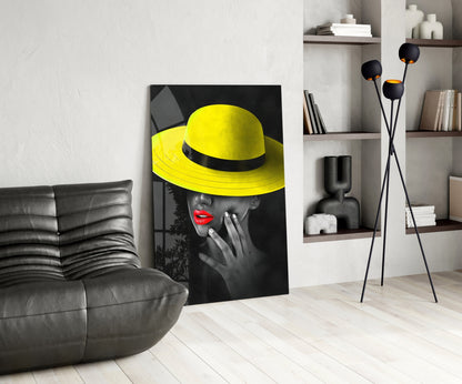 Yellow Hat Glass Wall Art displayed in modern living room with gray leather sofa, wooden shelving, and floor lamp.