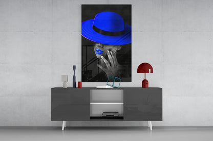 Blue hat glass wall art displayed above a gray media console, showing a black and white portrait with vibrant blue accents.