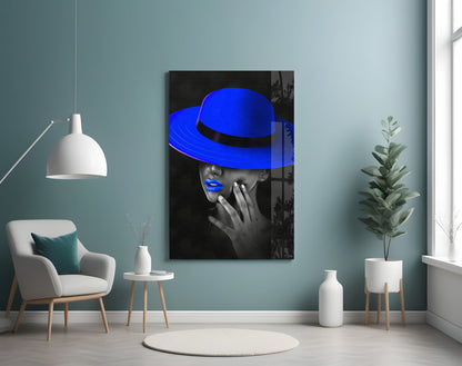 Blue Hat Glass Wall Art displayed on a teal wall in a minimalist room with white furniture and plants.