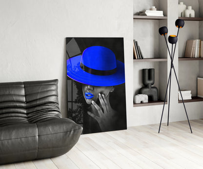 Modern living room interior featuring blue hat glass wall art leaning against white wall beside gray leather sofa.