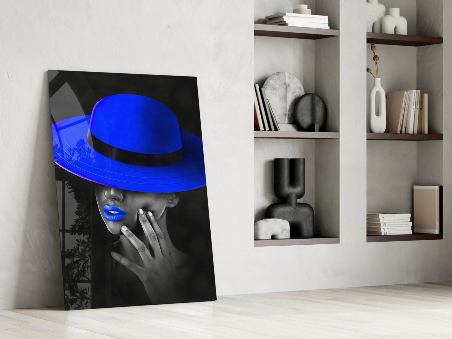 Blue Hat Glass Wall Art leaning against white wall next to shelving unit displaying decorative objects and books.