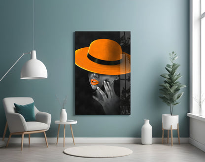 Orange Hat Glass Wall Art displayed on teal wall in modern living room with white chair and potted plant.