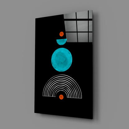 Black glass panel with turquoise circle, cyan semicircle, orange dots, and white concentric arc lines, displayed at an angle against gray background.