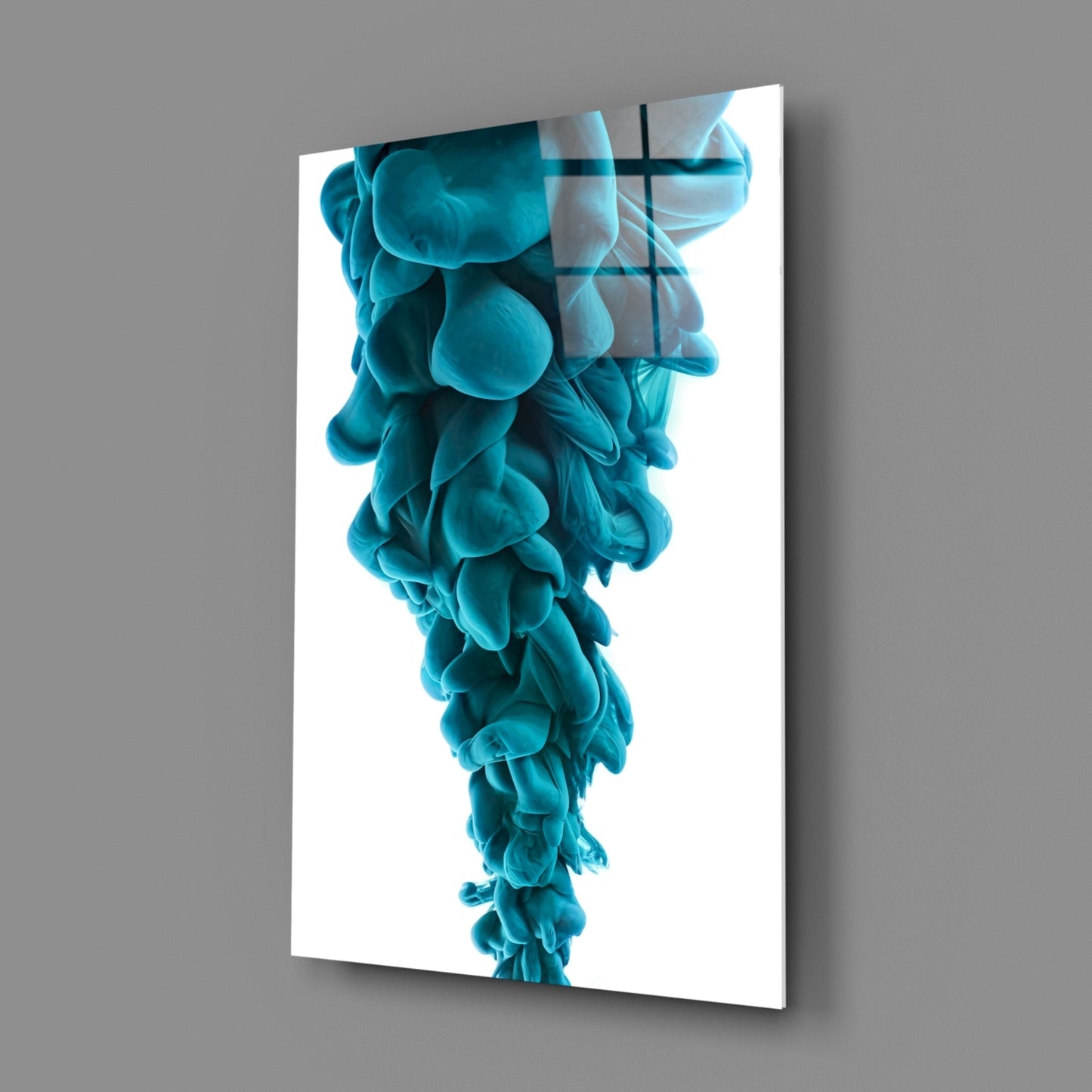 Angled view of vertical glass wall art displaying layered turquoise organic forms with geometric cross overlay on white background.