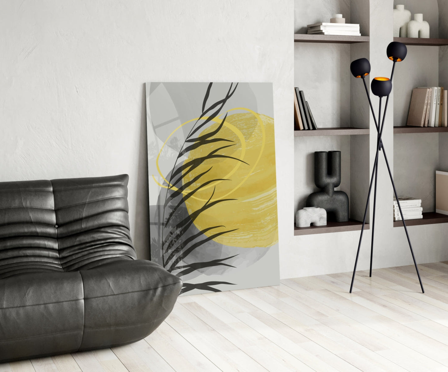 Modern living room with yellow and black botanical glass wall art leaning against white wall beside black leather chair.