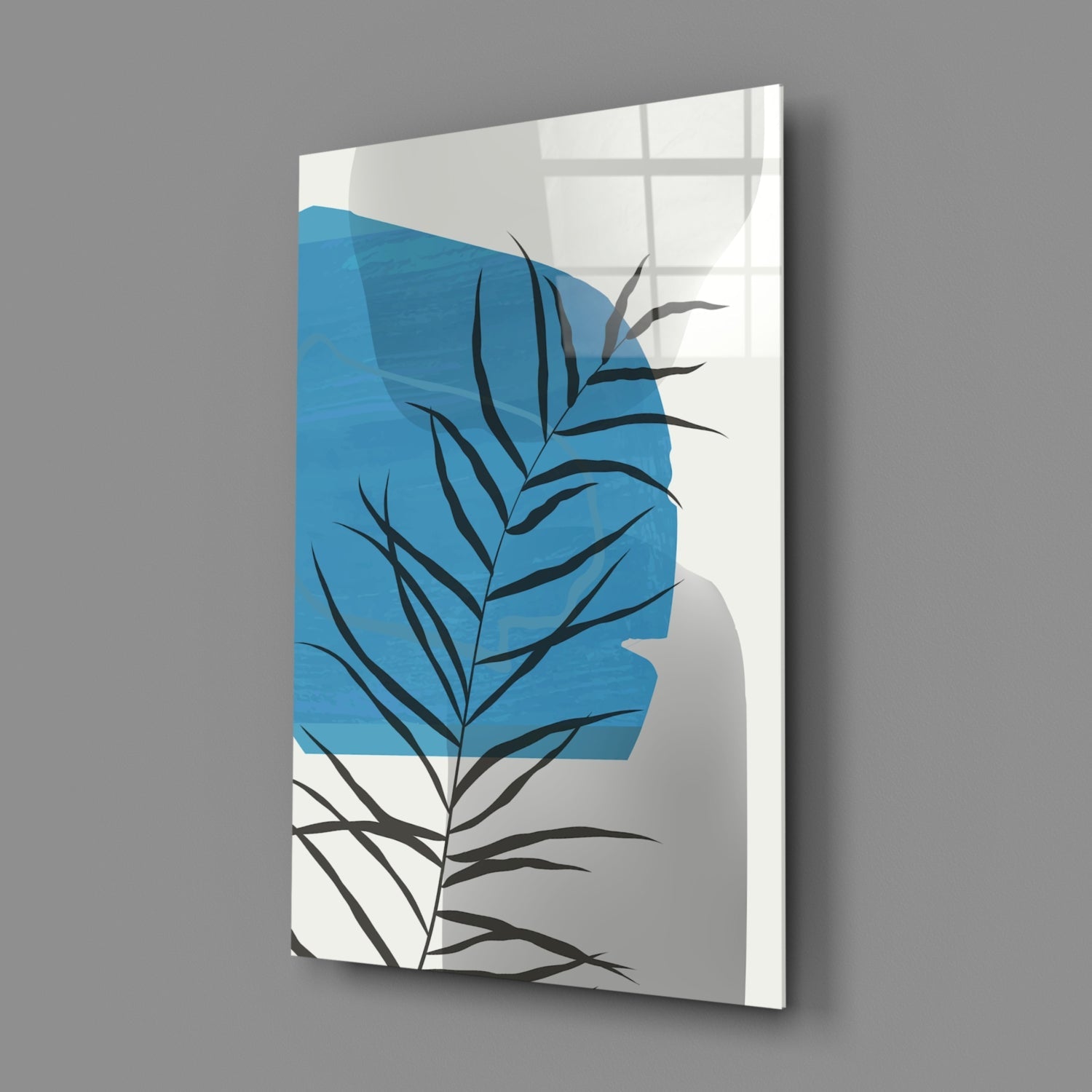 Angled perspective of glass wall art displaying black botanical branch against blue and white geometric background with window reflection.