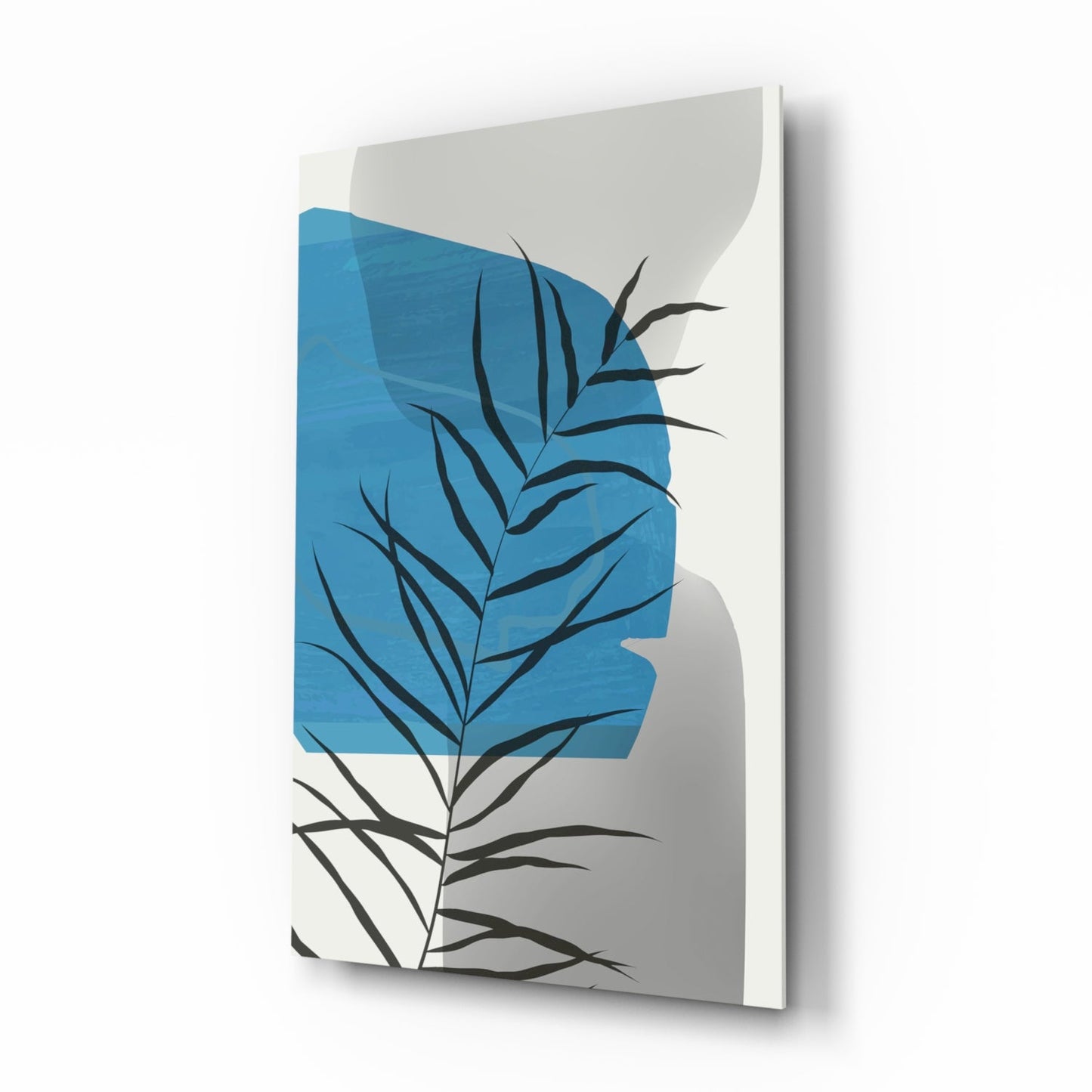 Angled side view of glass wall art featuring black botanical leaf silhouettes overlaying blue geometric shapes on cream background.