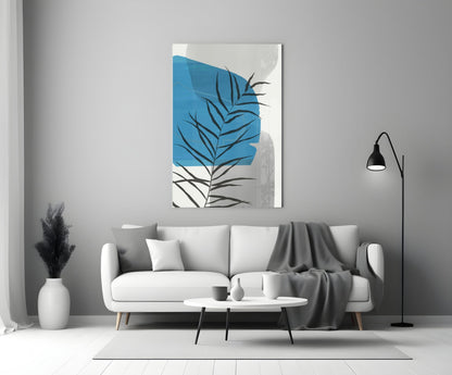 Modern living room with white sofa displaying blue and black leaf glass wall art above, styled with minimalist decor.