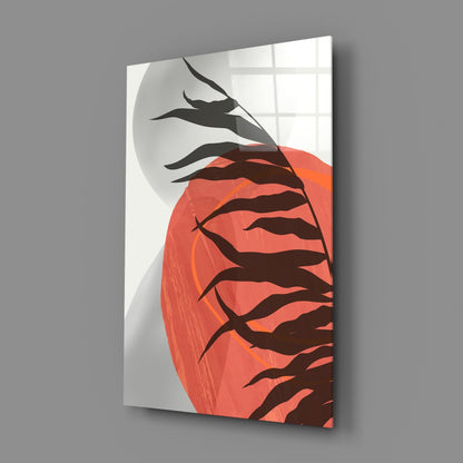 Angled view of glass wall art displaying red autumn leaves and black branch silhouettes against white background, mounted on gray wall.