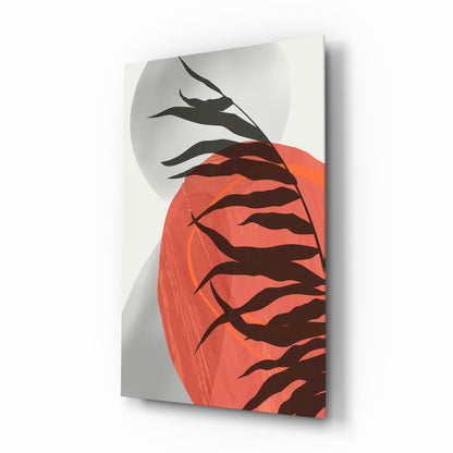 Glass wall art panel displaying stylized black leaf silhouettes against a large coral-red circular form on white background, mounted at angle showing depth and shadow.