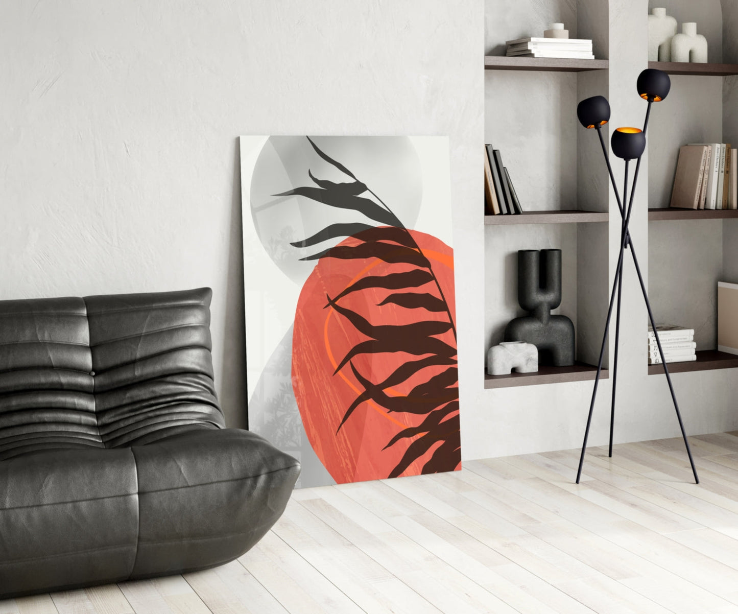 Modern living room interior displaying red and black glass wall art with branch motif leaning against white wall beside black leather chair.