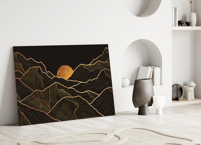 Black glass wall art with gold line-drawn mountains and sun, leaning against white wall in minimalist room setting.