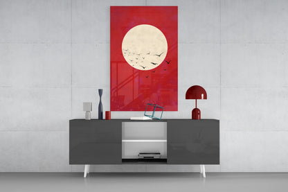 Red glass wall art featuring a cream moon with flying birds displayed above a gray media console in a modern living room setting.