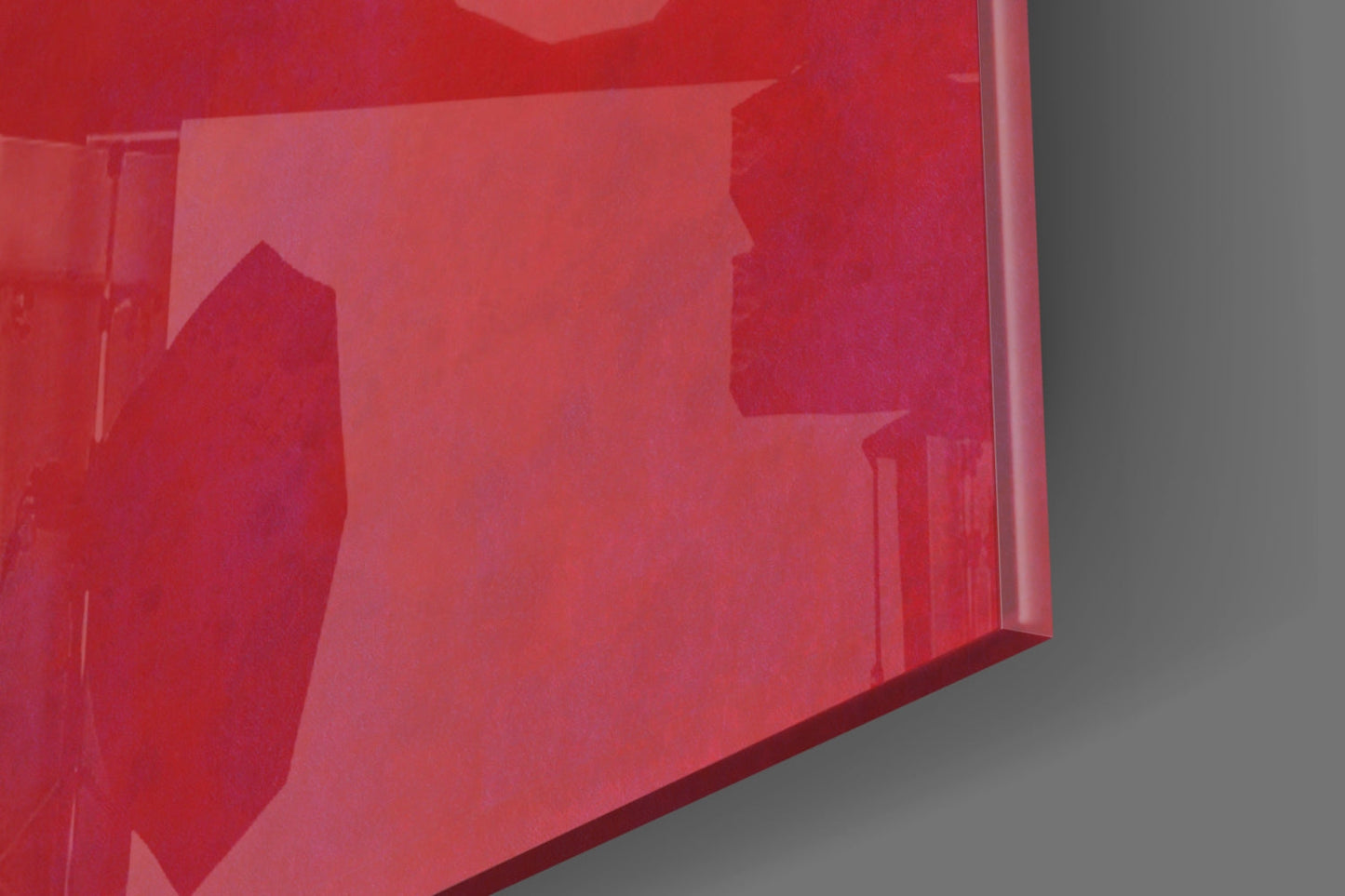 Close-up angle of red translucent glass wall art showing layered silhouettes and dimensional depth against gray background.