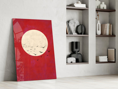 Red glass wall art leaning against white wall beside white shelving unit displaying decorative objects and books.