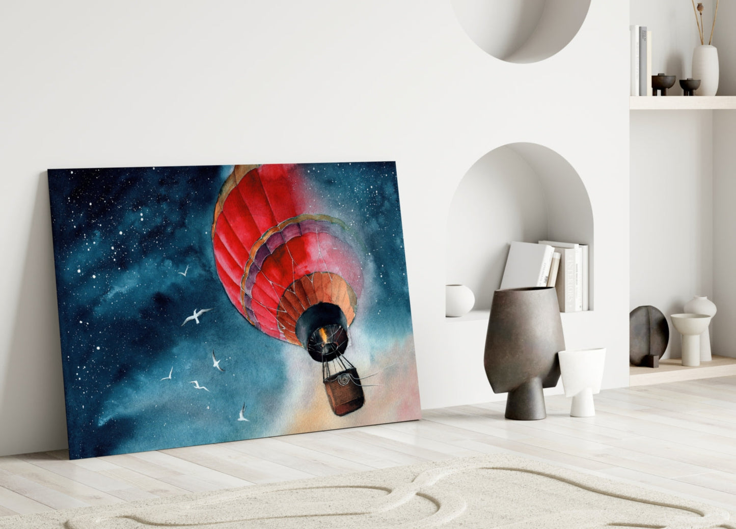 Red hot air balloon with basket ascending toward starry night sky, leaning against white wall in minimalist room setting.